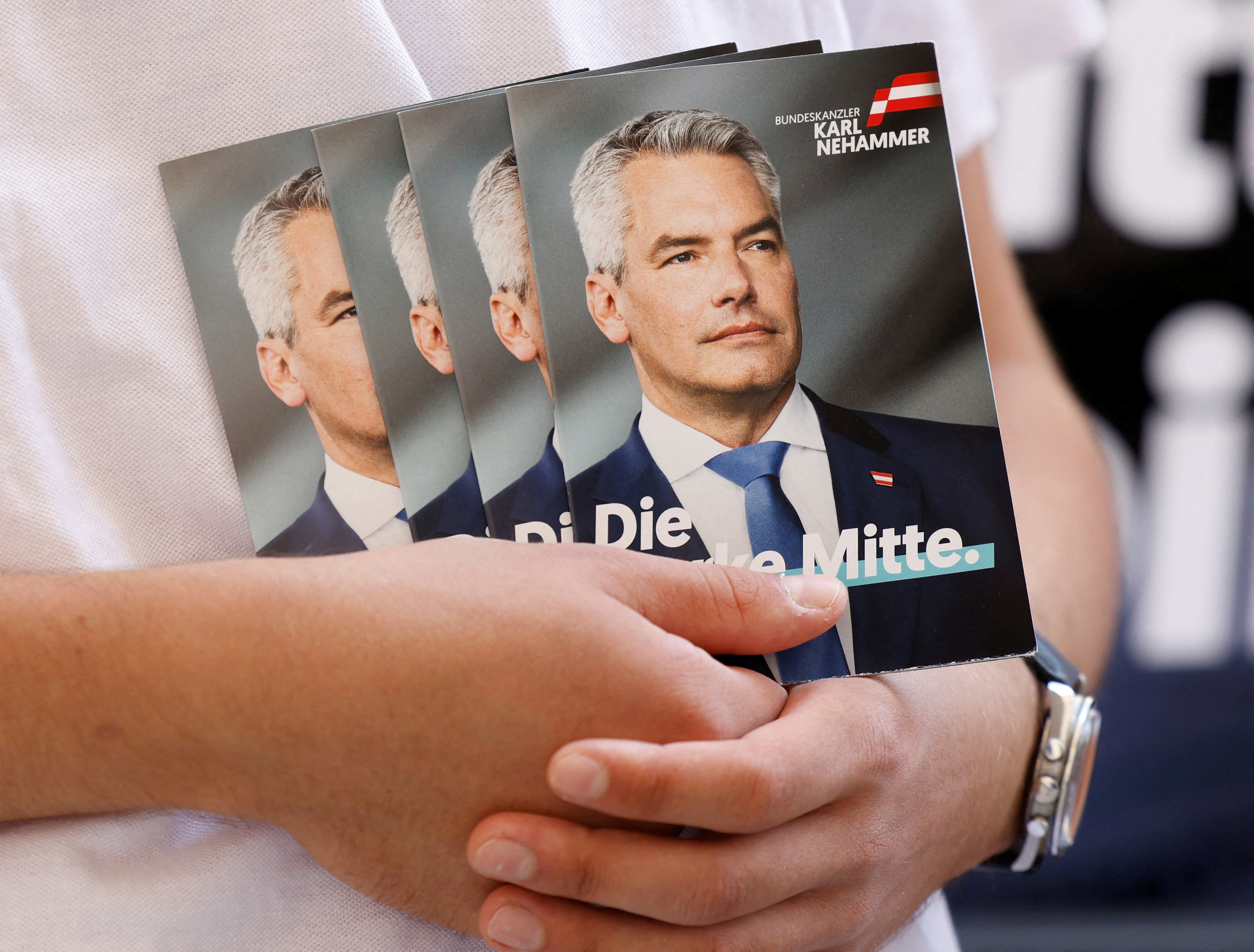 FILE PHOTO: A person holds pictures of Austrian Chancellor and head of Peoples Party Karl Nehammer in Vienna