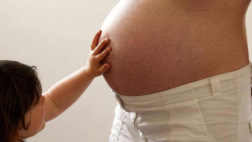 FILE PHOTO: A child touches her pregnant mother's stomach at the last stages of her pregnancy in Bordeaux