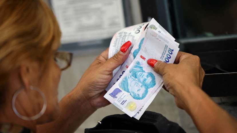 FILE PHOTO: A customer counts Argentine peso bills before checking out in a supermarket, in Buenos Aires