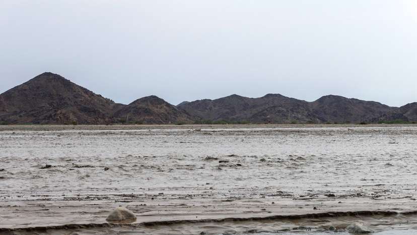 Flood water creates a channel, with the Red Sea mountains visible in the background, in Port Sudan