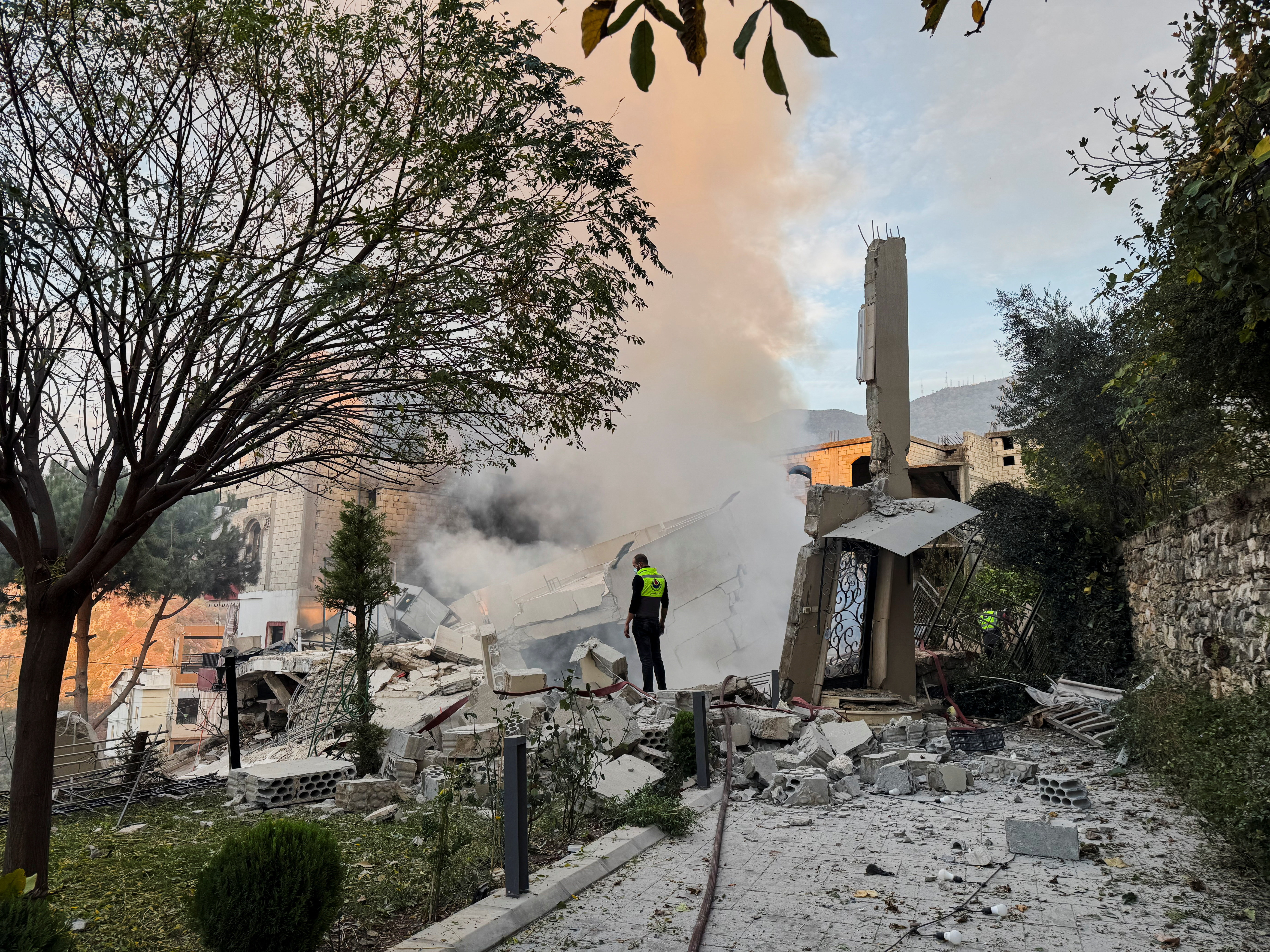 A civil defence member stands on rubble at a damaged site after Israel's military said it struck targets in two southern Lebanese towns on Thursday, in Jbaa