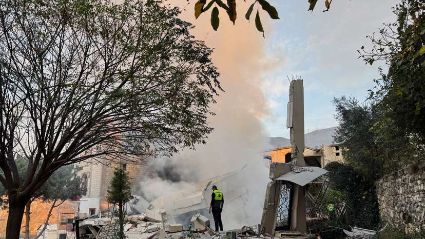 A civil defence member stands on rubble at a damaged site after Israel's military said it struck targets in two southern Lebanese towns on Thursday, in Jbaa