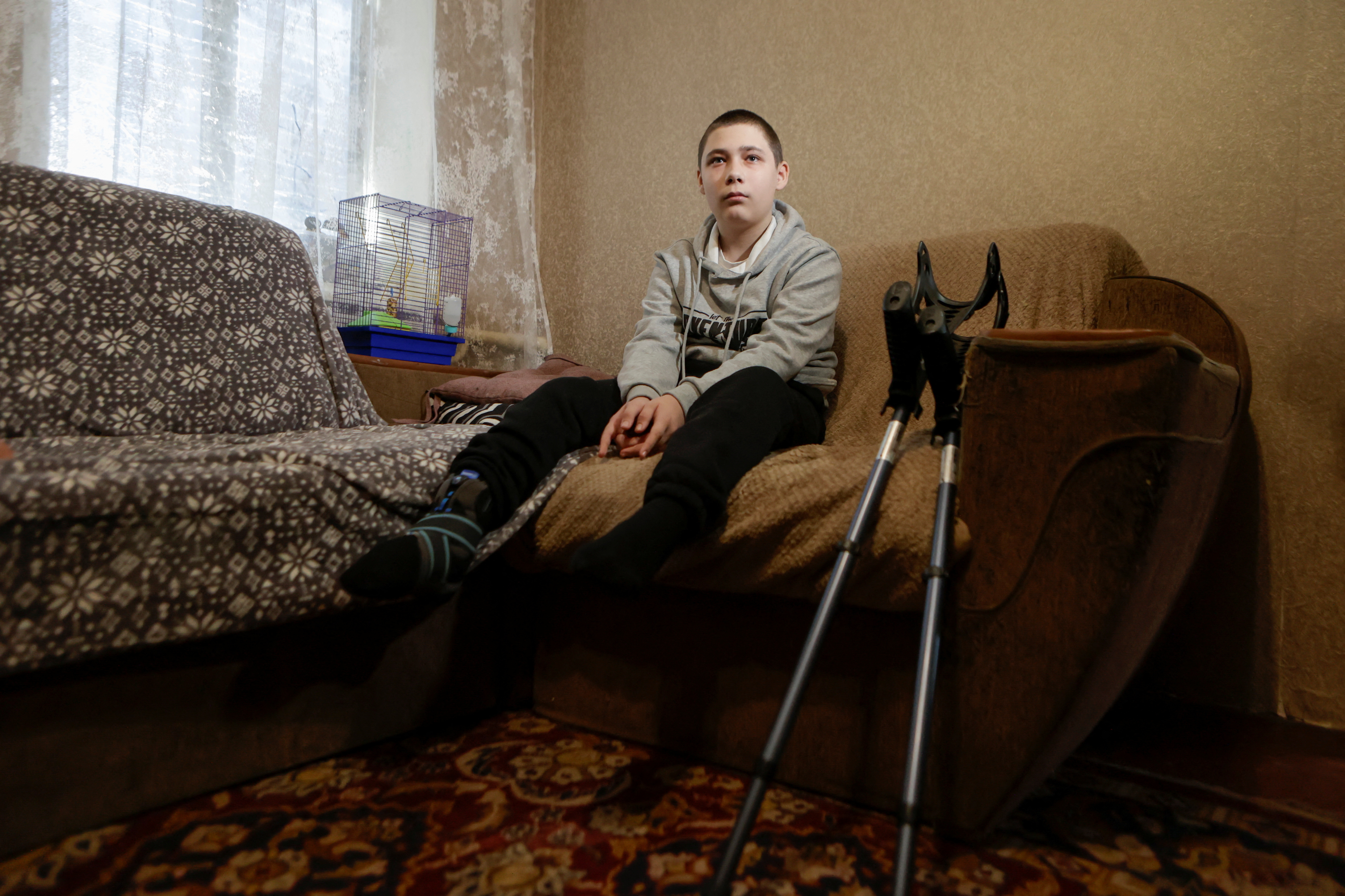 An injured, Nazar Mostovyi sits on a sofa inside of his house in the village of Nikopol