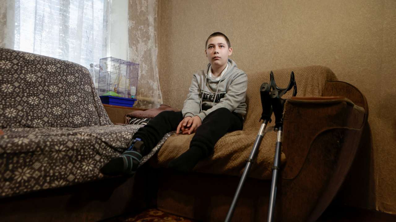 An injured, Nazar Mostovyi sits on a sofa inside of his house in the village of Nikopol