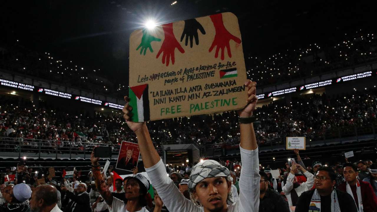 A man holds a placard with a slogan written on it during a solidarity gathering to show support for Palestinians in Kuala Lumpur