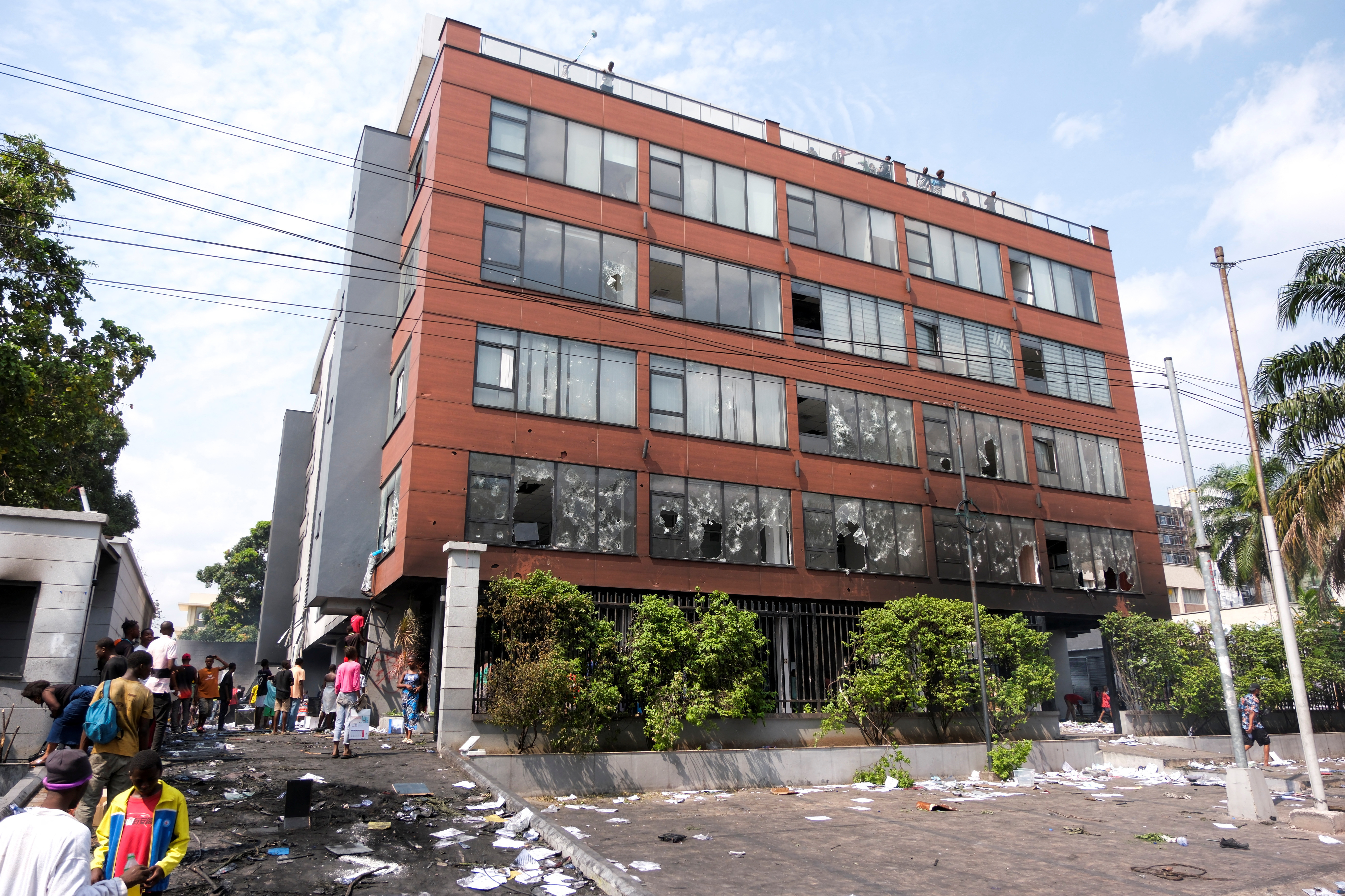 People stand outside of the Rwandan embassy, after the building was looted by protesters in Kinshasa