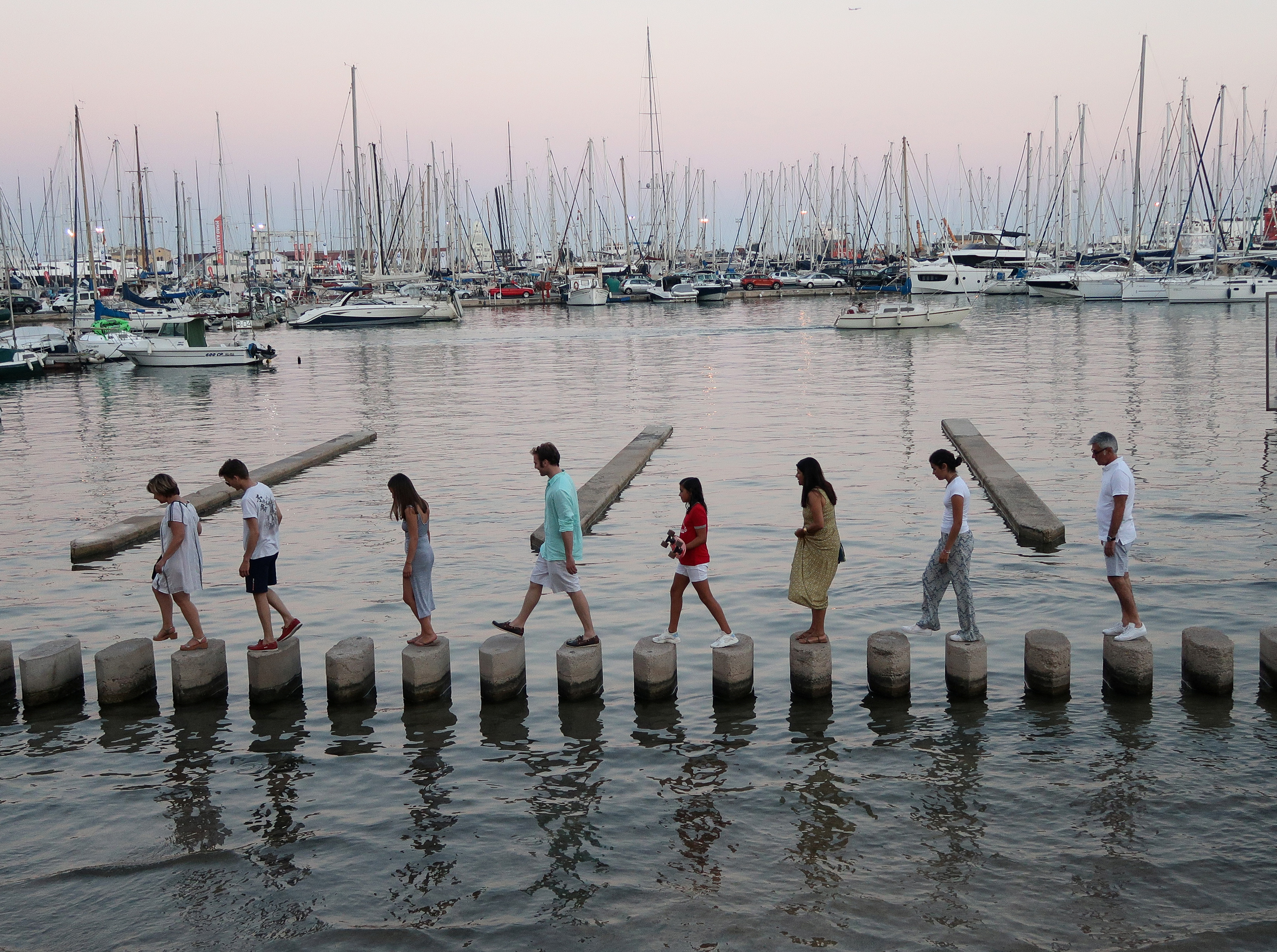 People walk across concrete posts to cross a section of the Marina in Palma de Mallorca