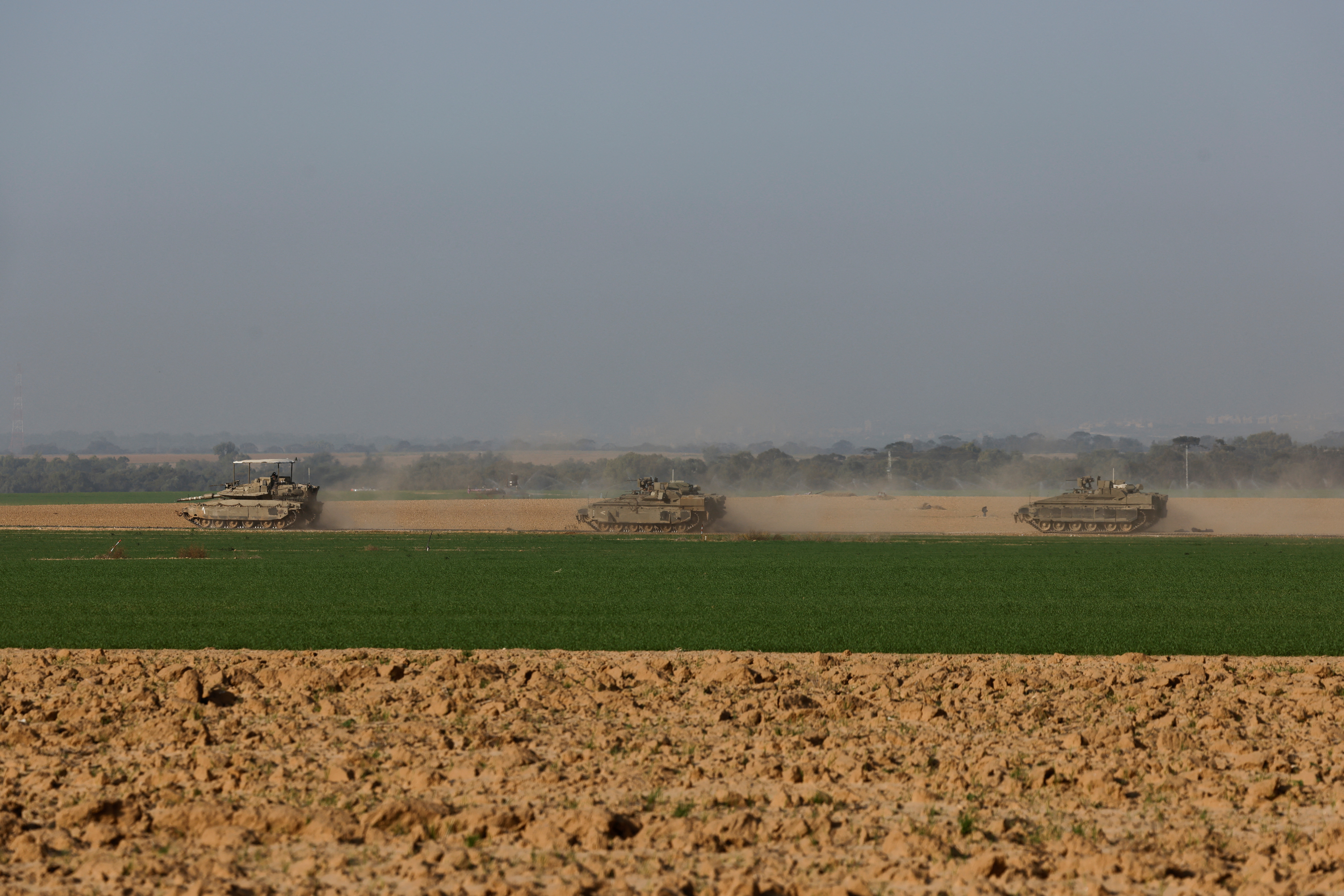 An Israeli tank and armored personnel carriers (APC) maneuver near Israel's border with southern Gaza, amid the ongoing conflict between Israel and the Palestinian Islamist group Hamas, in Israel