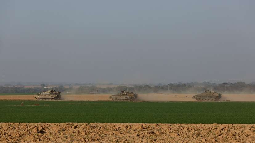 An Israeli tank and armored personnel carriers (APC) maneuver near Israel's border with southern Gaza, amid the ongoing conflict between Israel and the Palestinian Islamist group Hamas, in Israel
