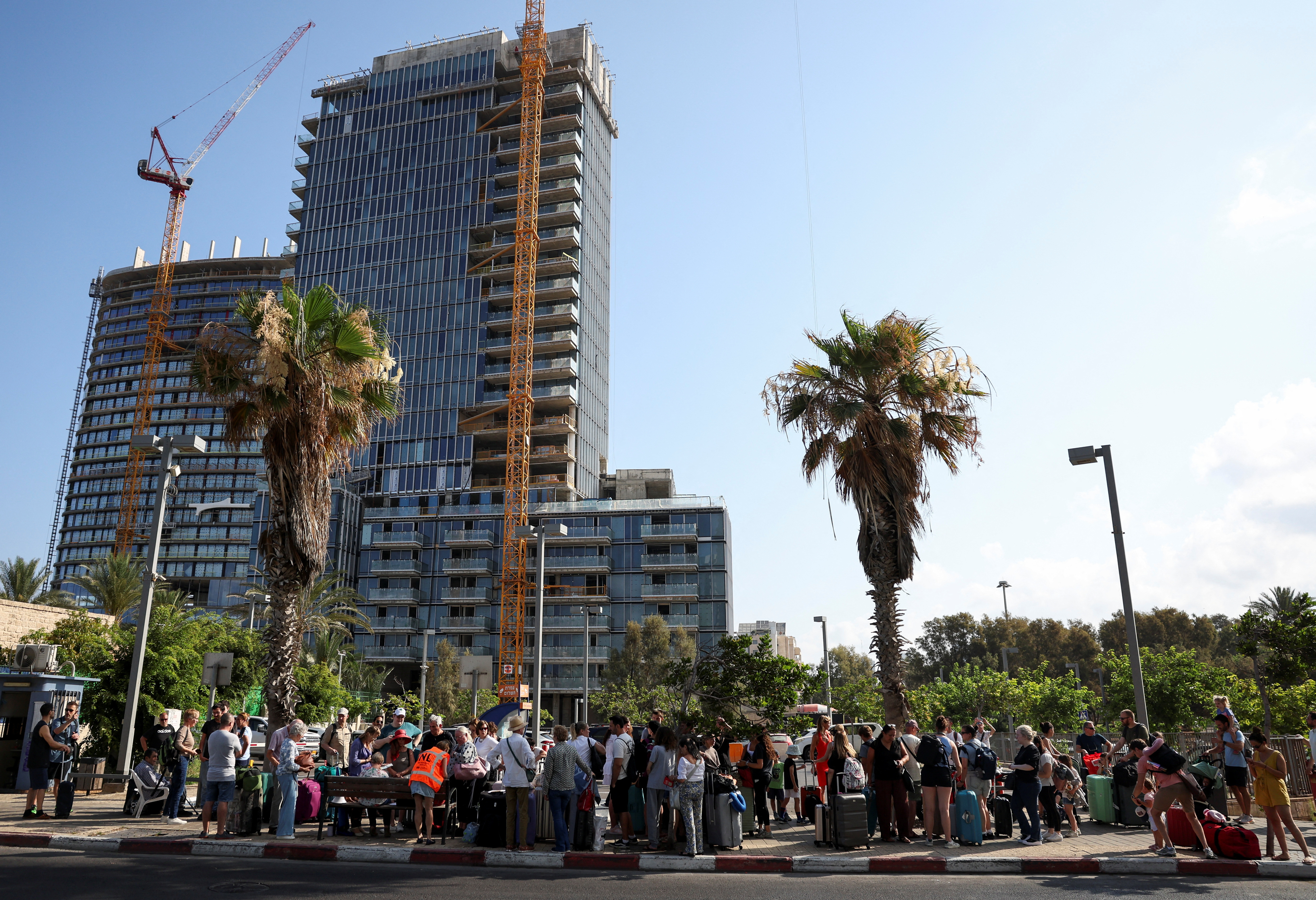 Foreign nationals wait in line to board a bus to be evacuated from Israel, amid the Iran-Israel conflict, in Tel Aviv