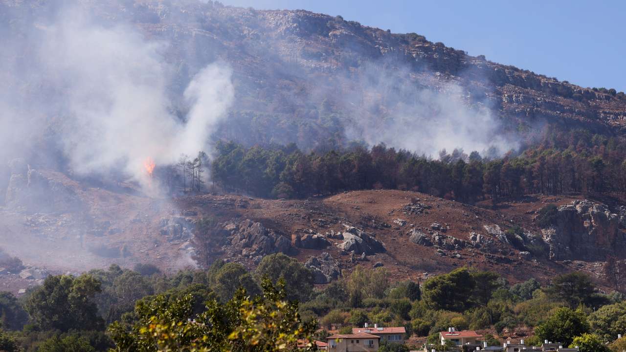 Smoke and flames are visible near homes in Kiryat Shmona after a rocket attack launched from Lebanon