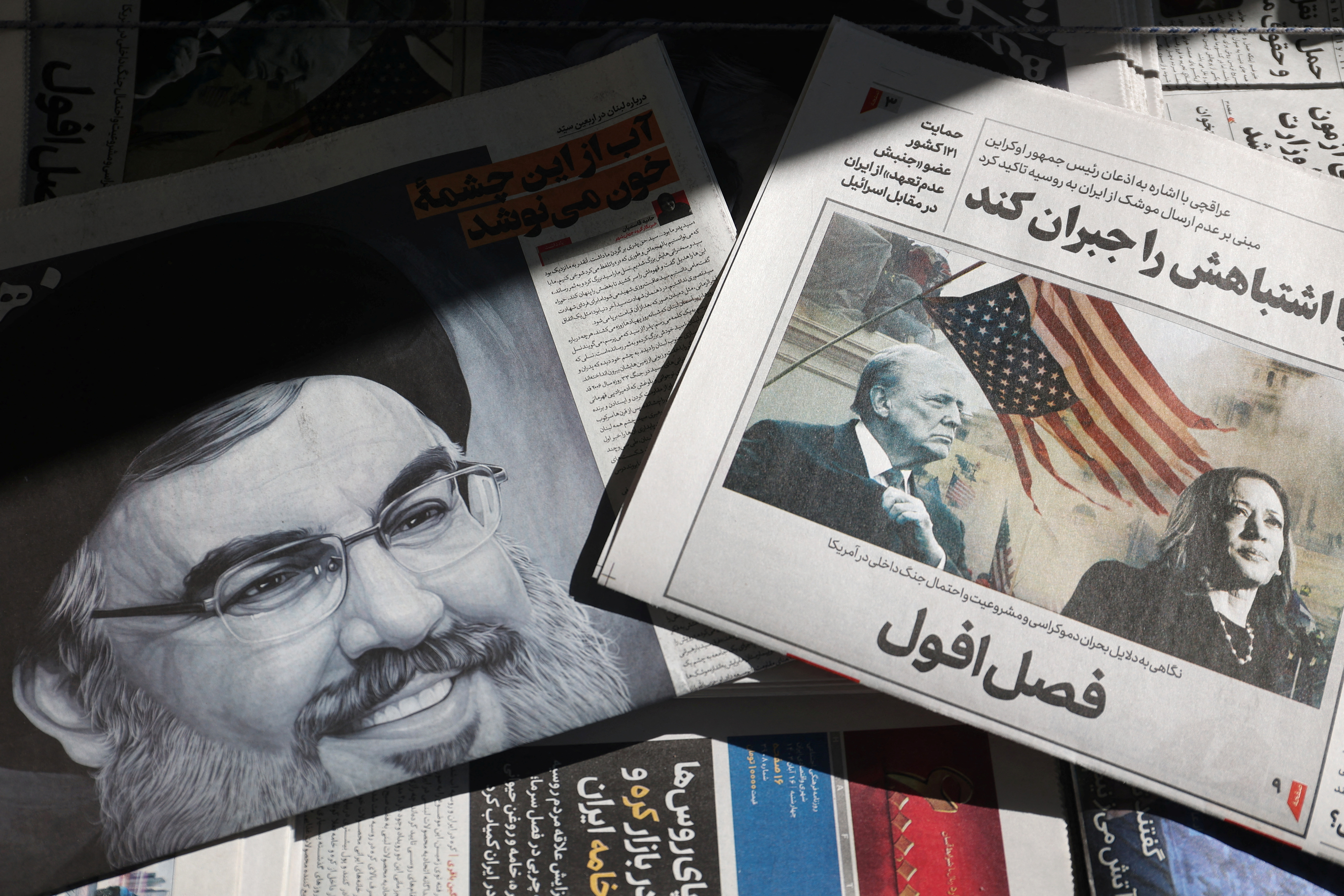A newspaper with a picture of Trump and Harris is seen next to a newspaper with a picture of late Lebanon's Hezbollah leader Nasrallah, in Tehran