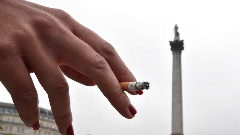 FILE PHOTO: A woman holds her cigarette as she smokes in Trafalgar Square in central London