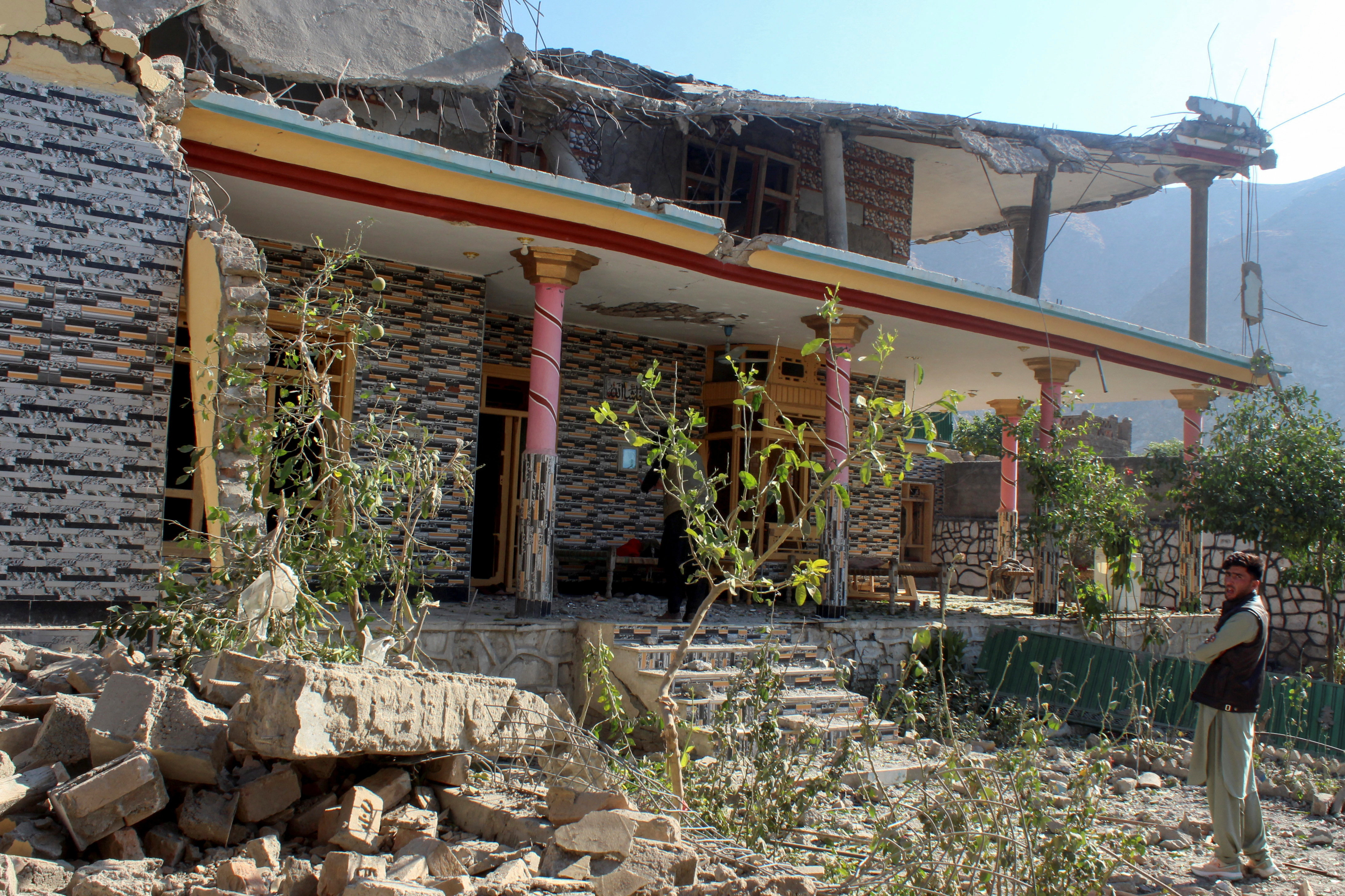 A man stands in front of a damaged house that the Afghan Taliban government said was damaged after Pakistan carried out raids, in Asadabad