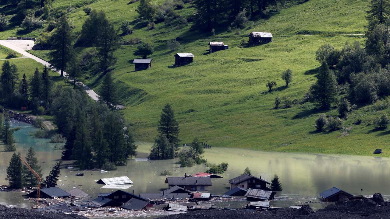 A few remaining houses are seen after a massive rock and ice slide covered most of the village of Blatten