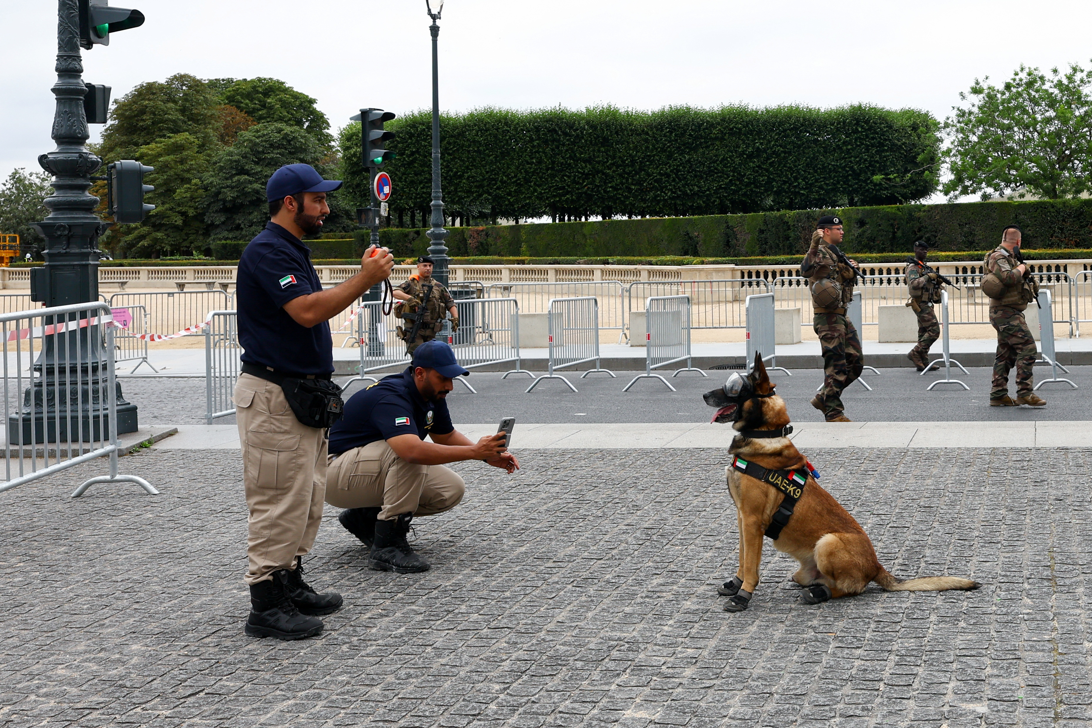 Law enforcement officer photographs dog as members of special task force walk past, at Louvre in Paris