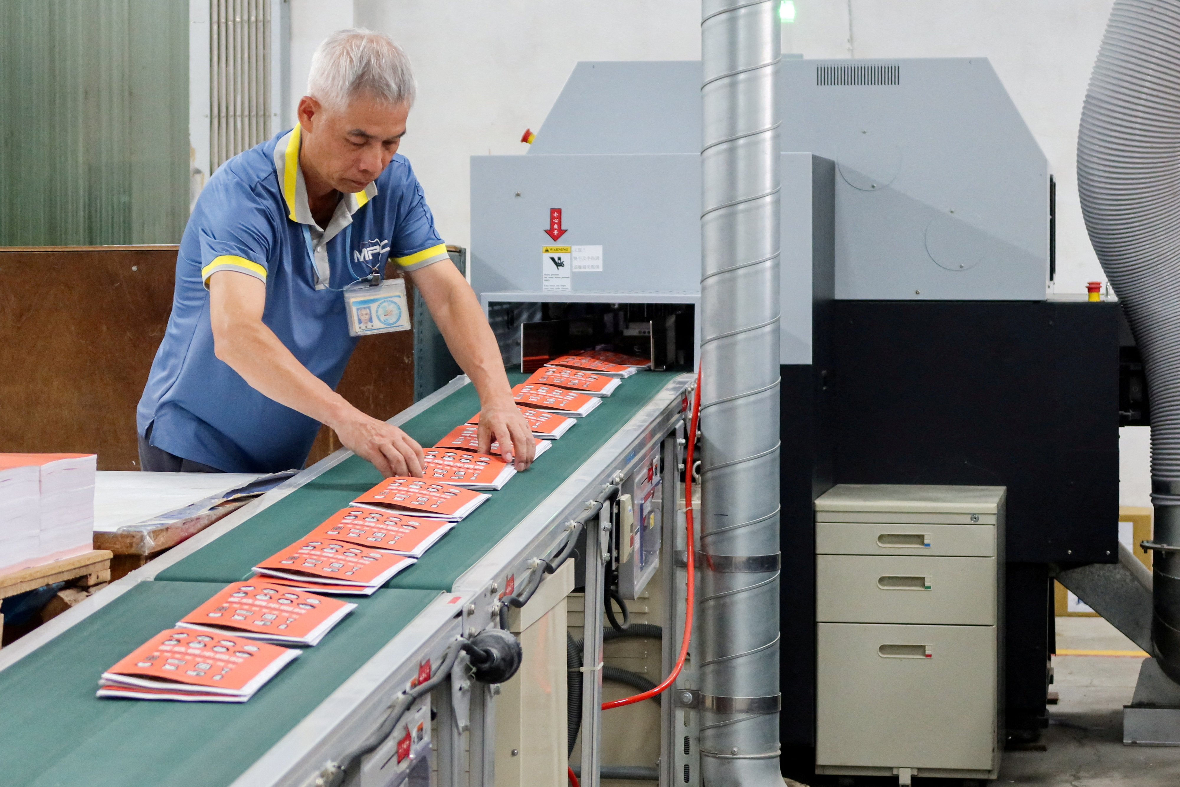 A worker handles copies of Taiwan's updated civil defence handbook at a printing house in Taoyuan
