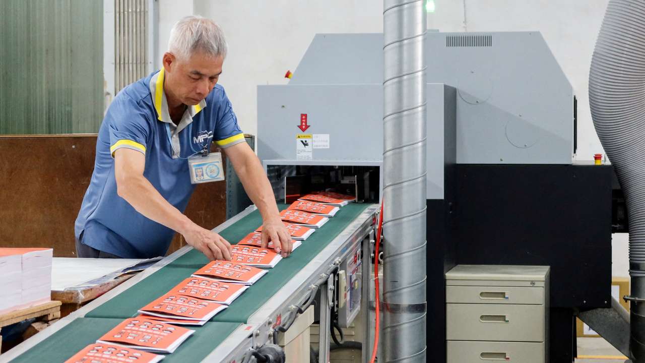 A worker handles copies of Taiwan's updated civil defence handbook at a printing house in Taoyuan