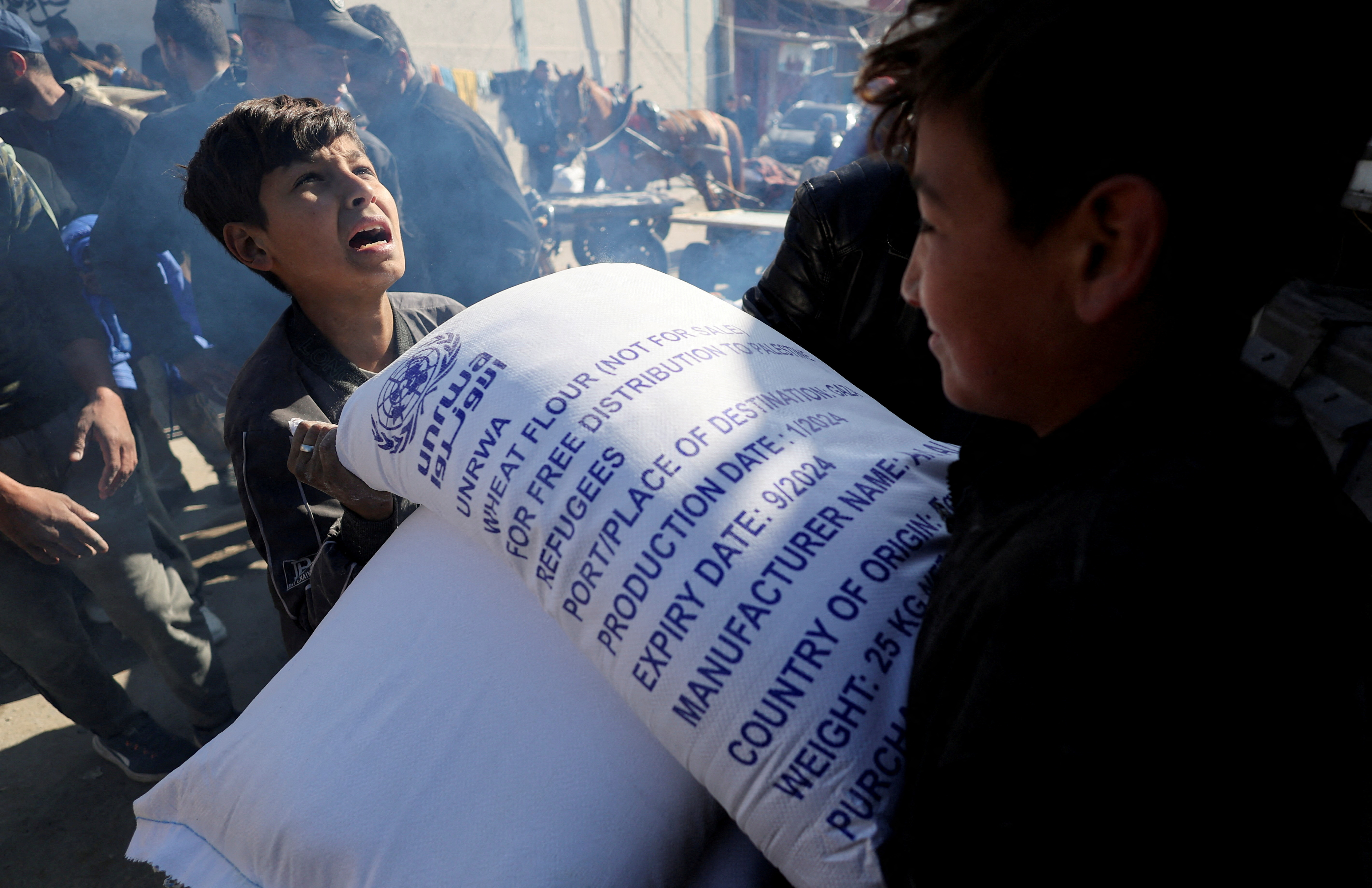 FILE PHOTO: Palestinians receive bags of flour distributed by UNRWA in Rafah