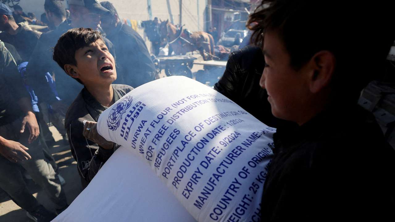 FILE PHOTO: Palestinians receive bags of flour distributed by UNRWA in Rafah