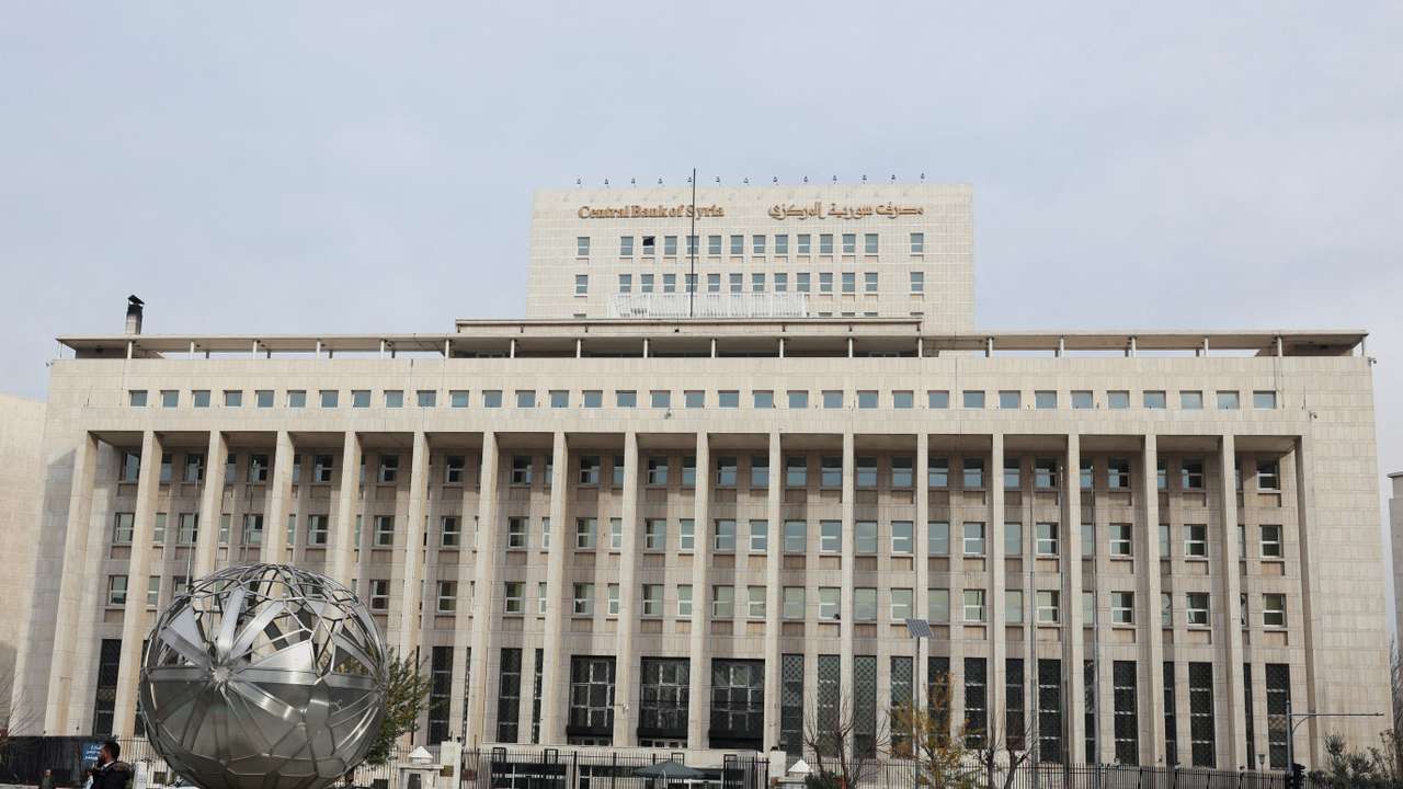 People and cars are seen in front of the Central Bank of Syria in Damascus