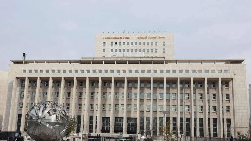 People and cars are seen in front of the Central Bank of Syria in Damascus