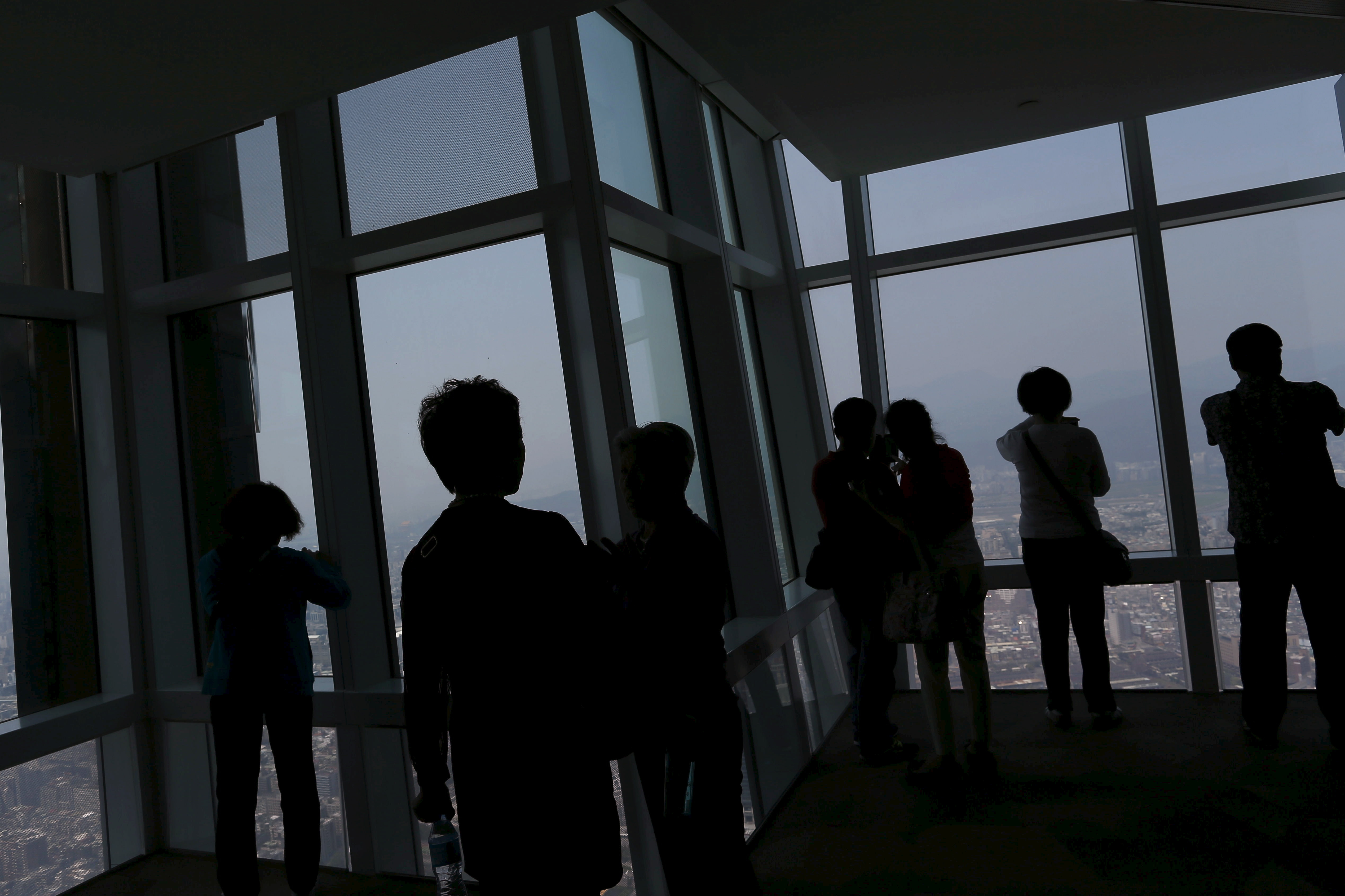 Tourists take photos of the city skyline from the Taipei 101 skyscraper building in Taipei, Taiwan