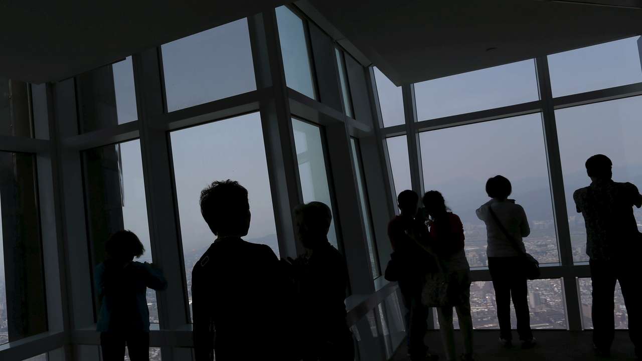 Tourists take photos of the city skyline from the Taipei 101 skyscraper building in Taipei, Taiwan