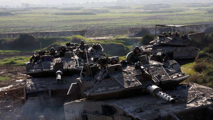 Israeli soldiers ride tanks while moving out of the Gaza Strip, as seen from southern Israel