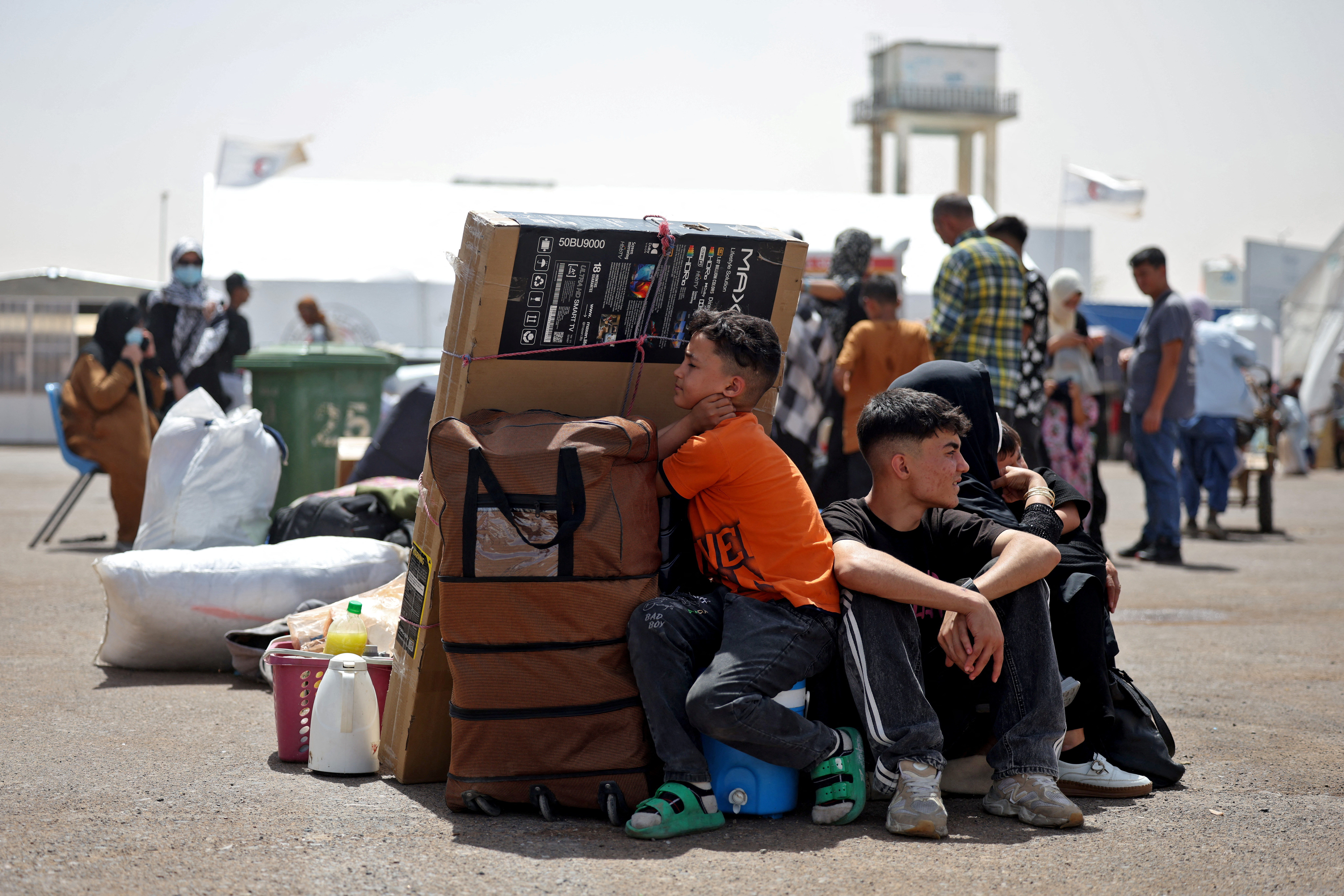 An Afghan family deported from Iran rests with their belongings at a camp for returning migrants near Islam Qala border crossing