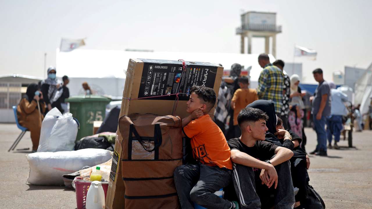 An Afghan family deported from Iran rests with their belongings at a camp for returning migrants near Islam Qala border crossing