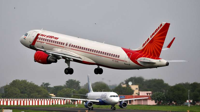 An Air India Airbus A320 aircraft takes off as an IndiGo Airlines aircraft waits for clearance at the Sardar Vallabhbhai Patel International Airport in Ahmedabad