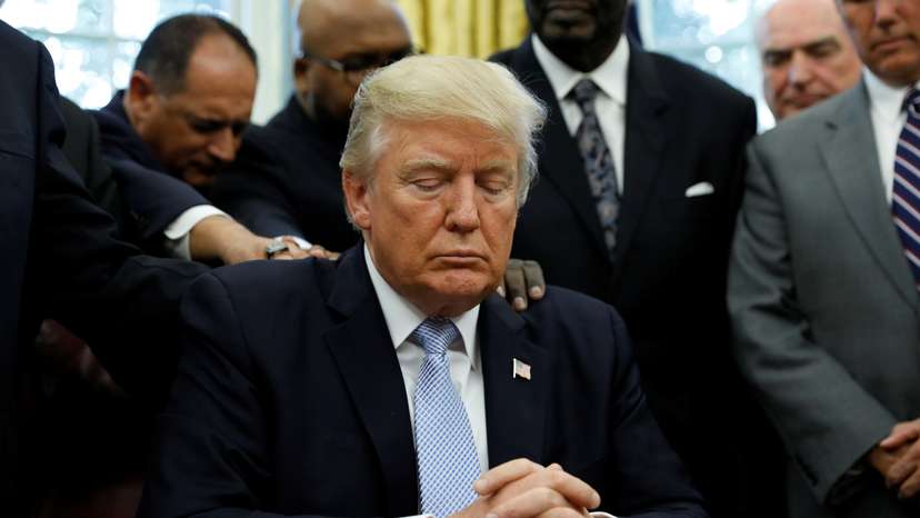 Faith leaders place their hands on the shoulders of U.S. President Trump as he takes part in a prayer for those affected by Hurricane Harvey in the Oval Office of the White House in Washington