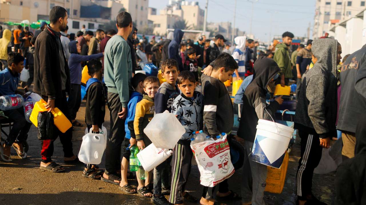 Palestinian children queue as they wait to collect drinking water, amid shortages of drinking water, as the conflict between Israel and Hamas continues, in Rafah