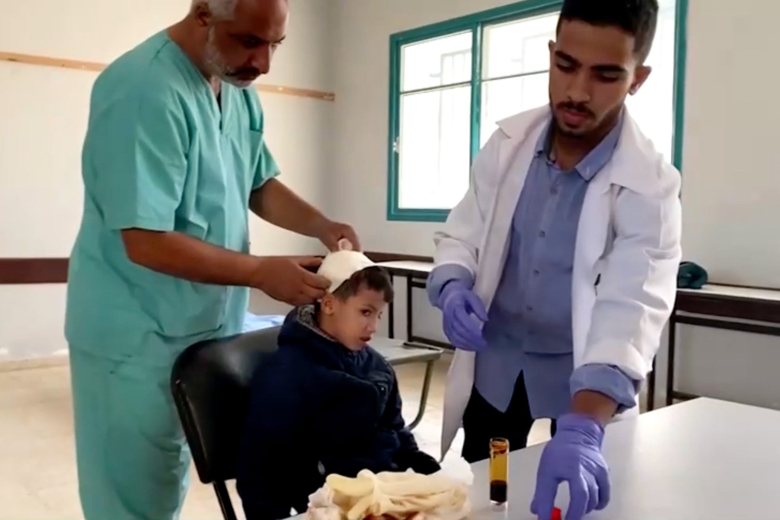 Doctors attend to a patient at a field clinic inside a central Gaza school in Deir Al-Balah, in this screengrab taken from a video.