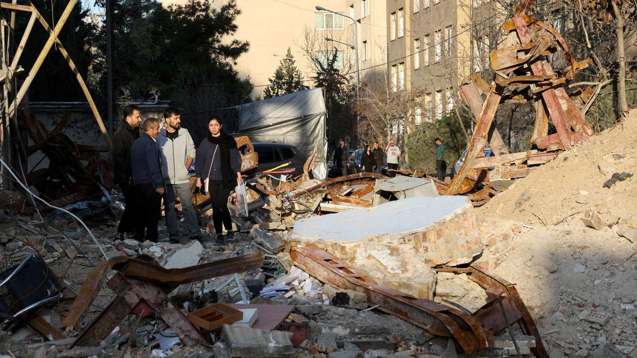 People look at a destroyed building following a strike, in Tehran