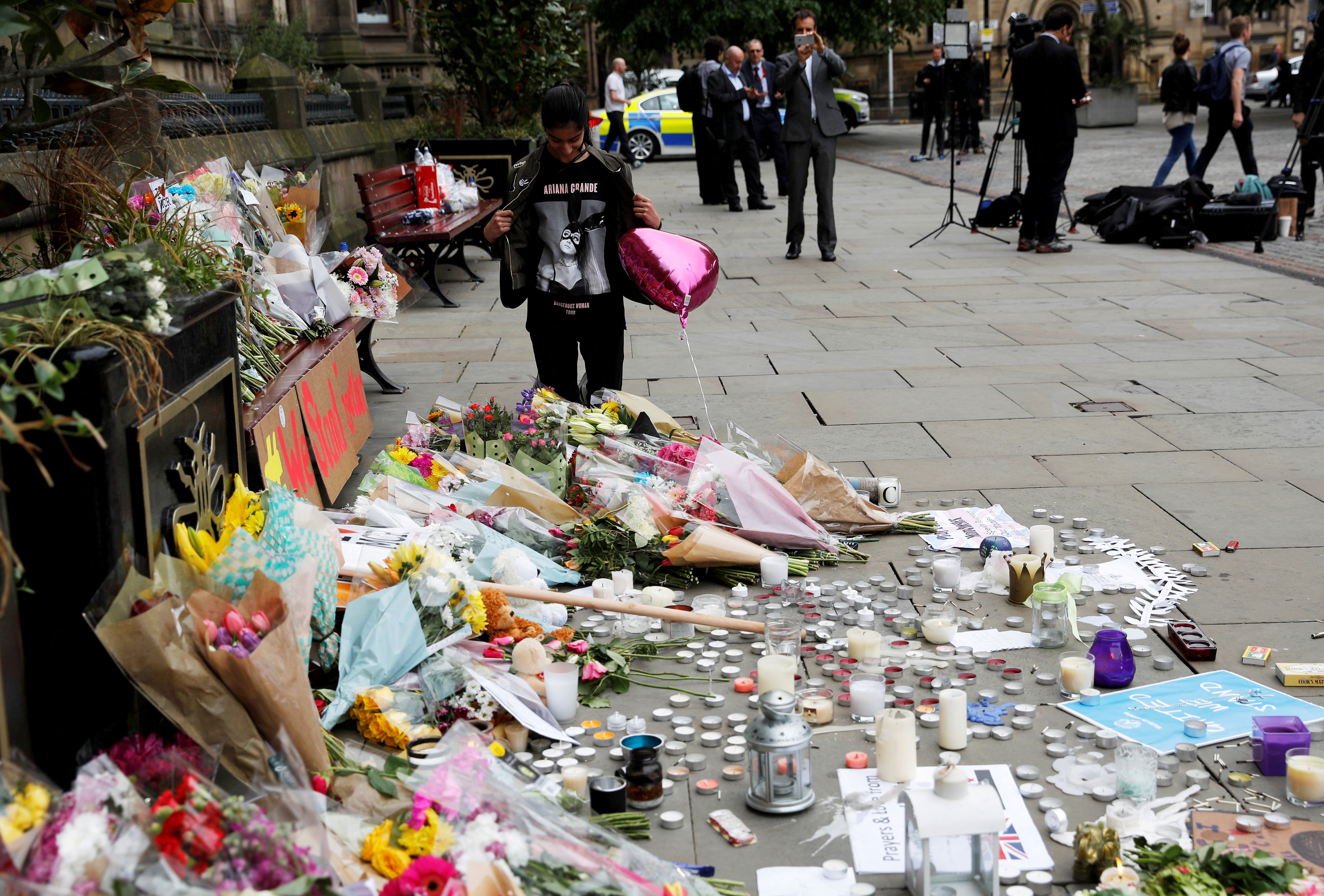 FILE PHOTO: An Ariana Grande fan stands next to floral tributes left for the victims of an attack on concert goers at Manchester Arena, in St Ann's Square, in Manchester