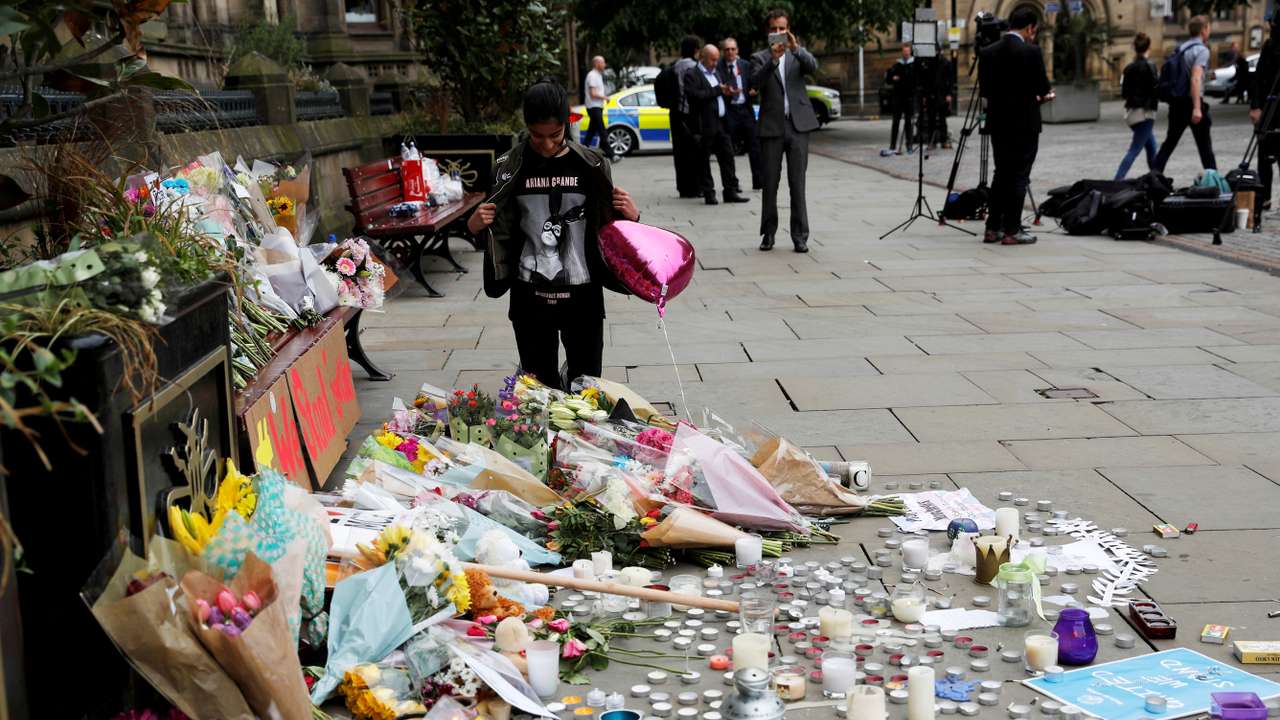 FILE PHOTO: An Ariana Grande fan stands next to floral tributes left for the victims of an attack on concert goers at Manchester Arena, in St Ann's Square, in Manchester