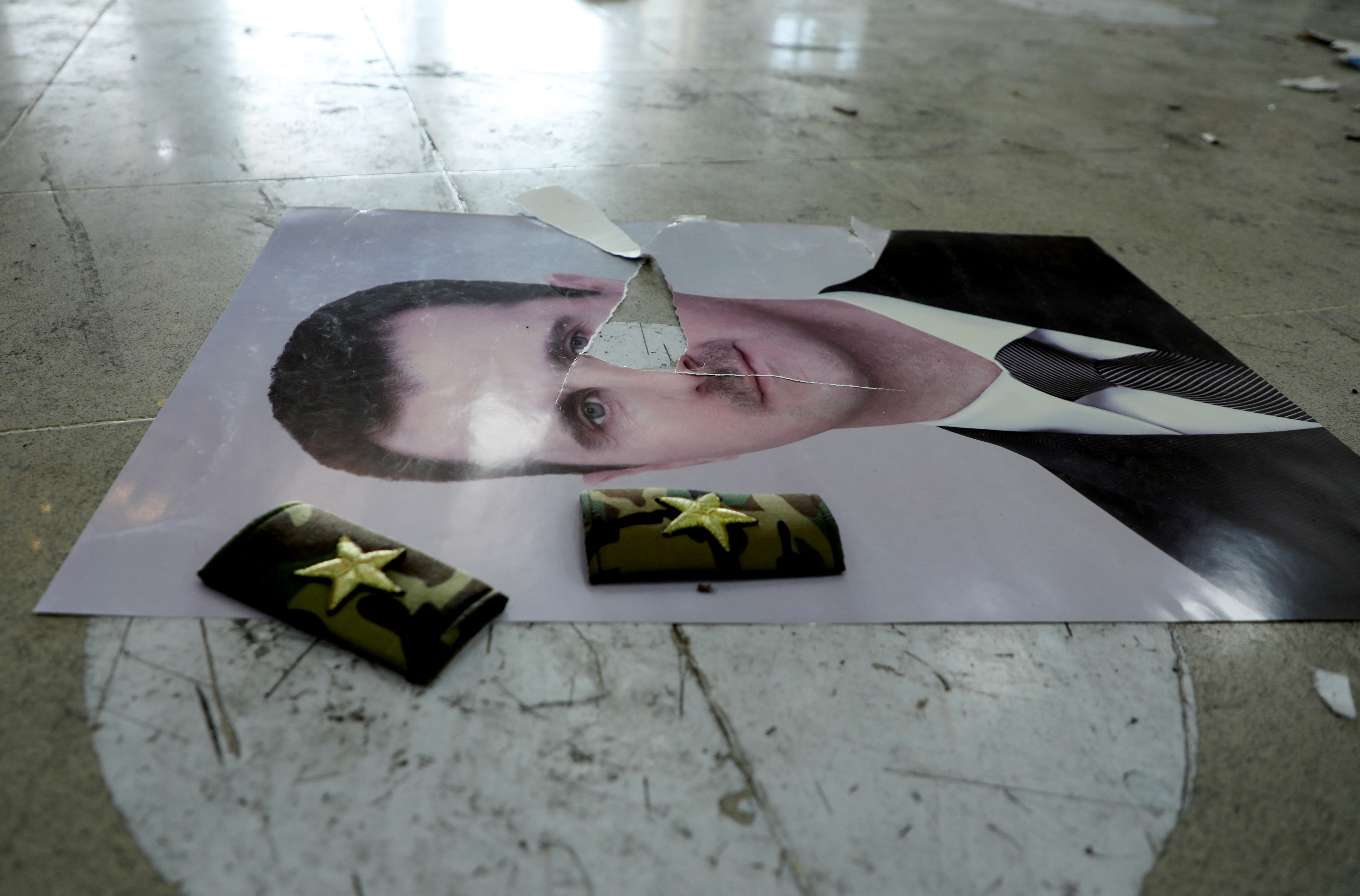 A damaged picture of Syria's Bashar al-Assad lies on the floor inside Qamishli international airport