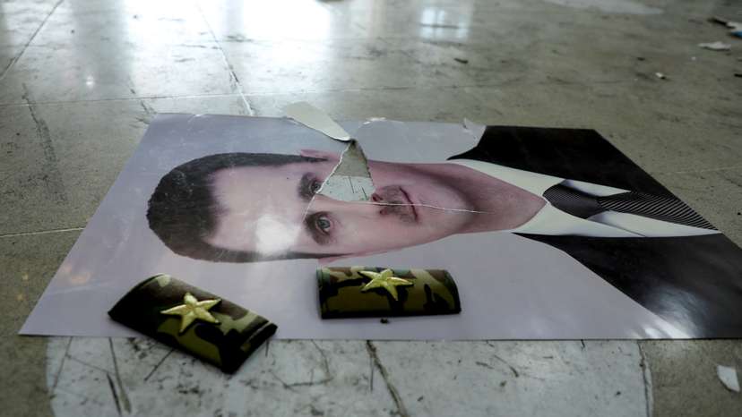A damaged picture of Syria's Bashar al-Assad lies on the floor inside Qamishli international airport