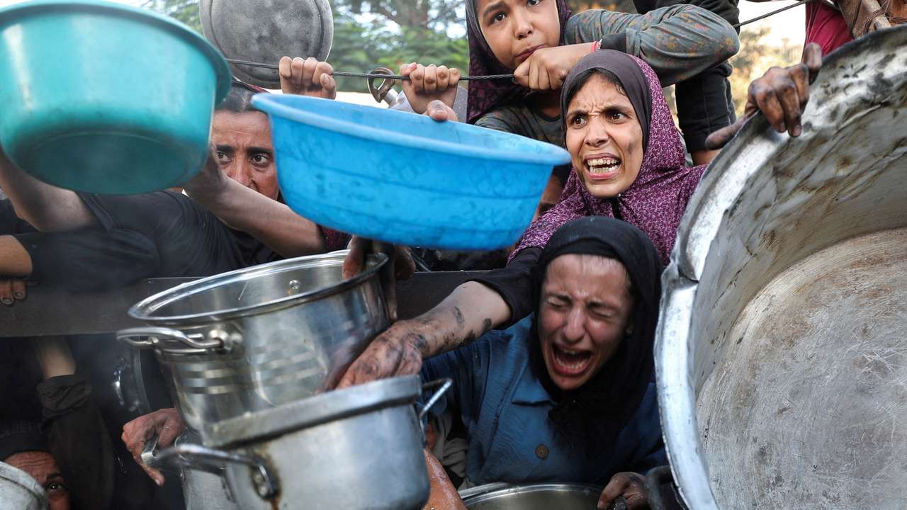 FILE PHOTO: Palestinians wait to receive food from a charity kitchen, amid a hunger crisis, in Gaza City