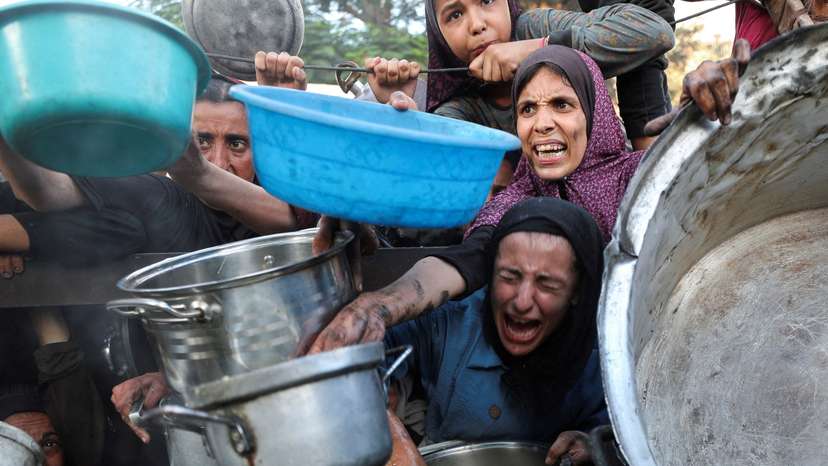 FILE PHOTO: Palestinians wait to receive food from a charity kitchen, amid a hunger crisis, in Gaza City
