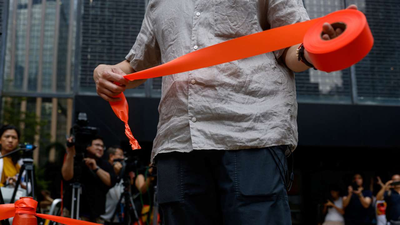 A police holds a cordon line outside District Court ahead of the verdict in a landmark sedition trial against two former editors of now-shuttered online media Stand News, in Hong Kong