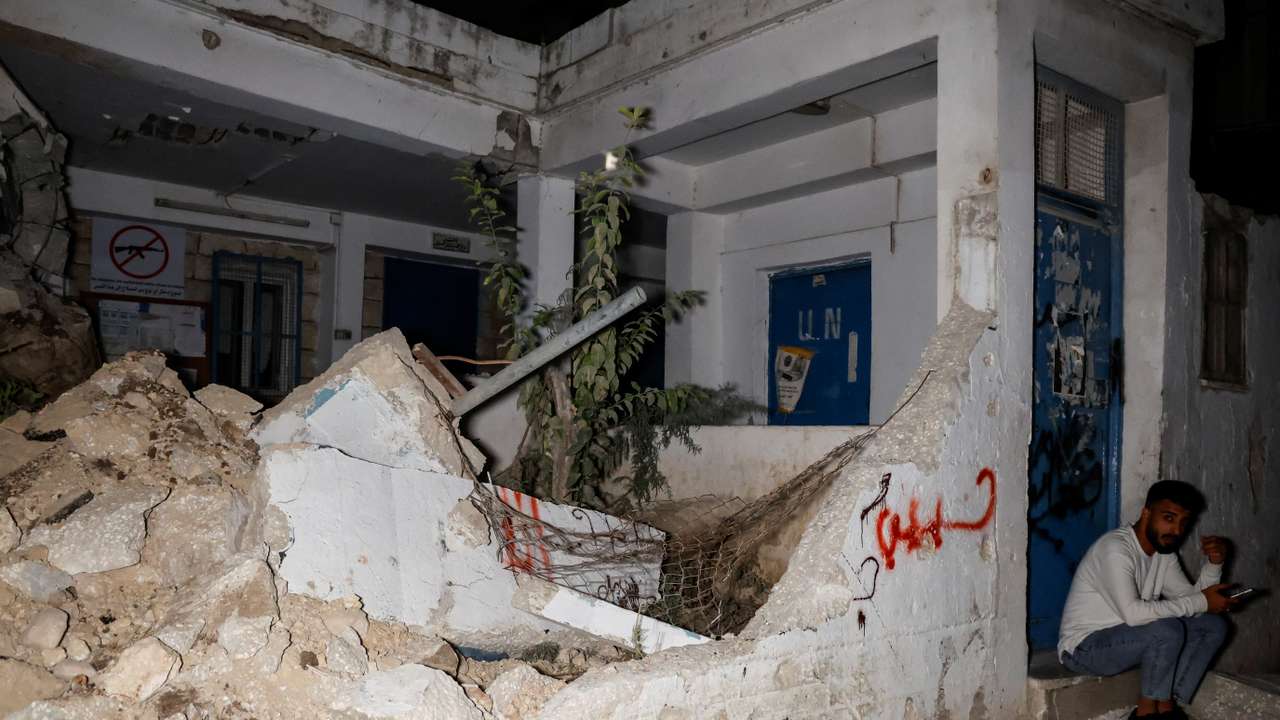 A man sits in front of a health clinic that belonged to the United Nations Relief and Works Agency for Refugees (UNRWA) in Nour Shams Camp, Tulkarm