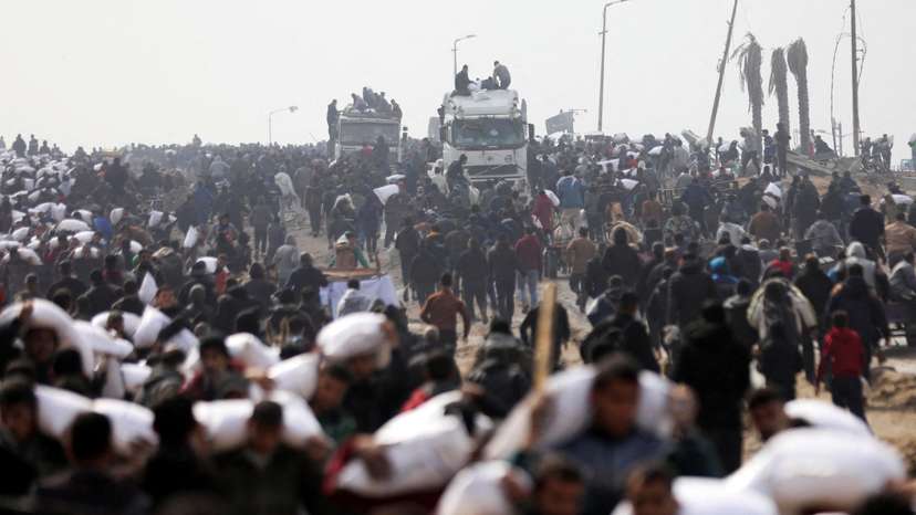 FILE PHOTO: Palestinians carry bags of flour they grabbed from an aid truck near an Israeli checkpoint in Gaza City