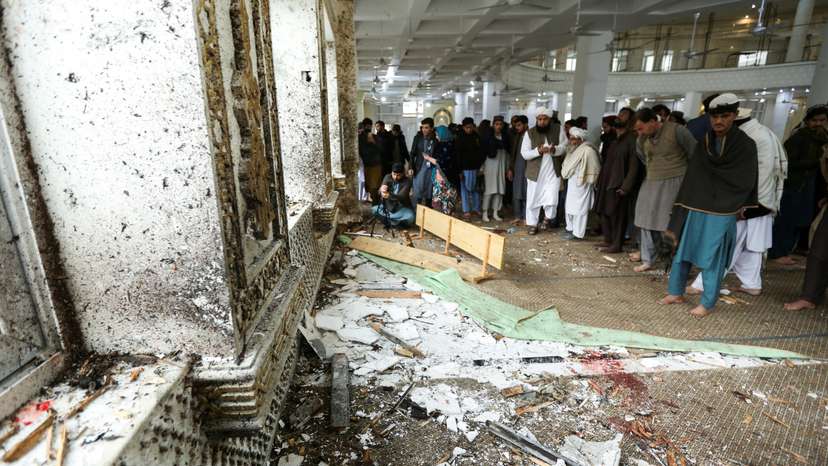 People inspect damage, at the site of a suicide bomber attack, on the day of Friday prayers, at an Islamic seminary in Akora Khattak