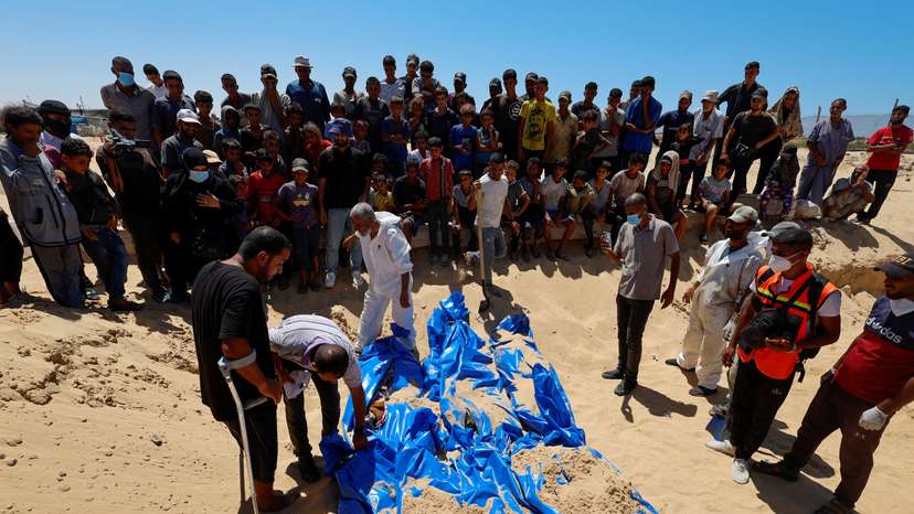 People bury the bodies of unidentified Palestinians at a mass grave after the bodies were handed over by Israel, in Khan Younis