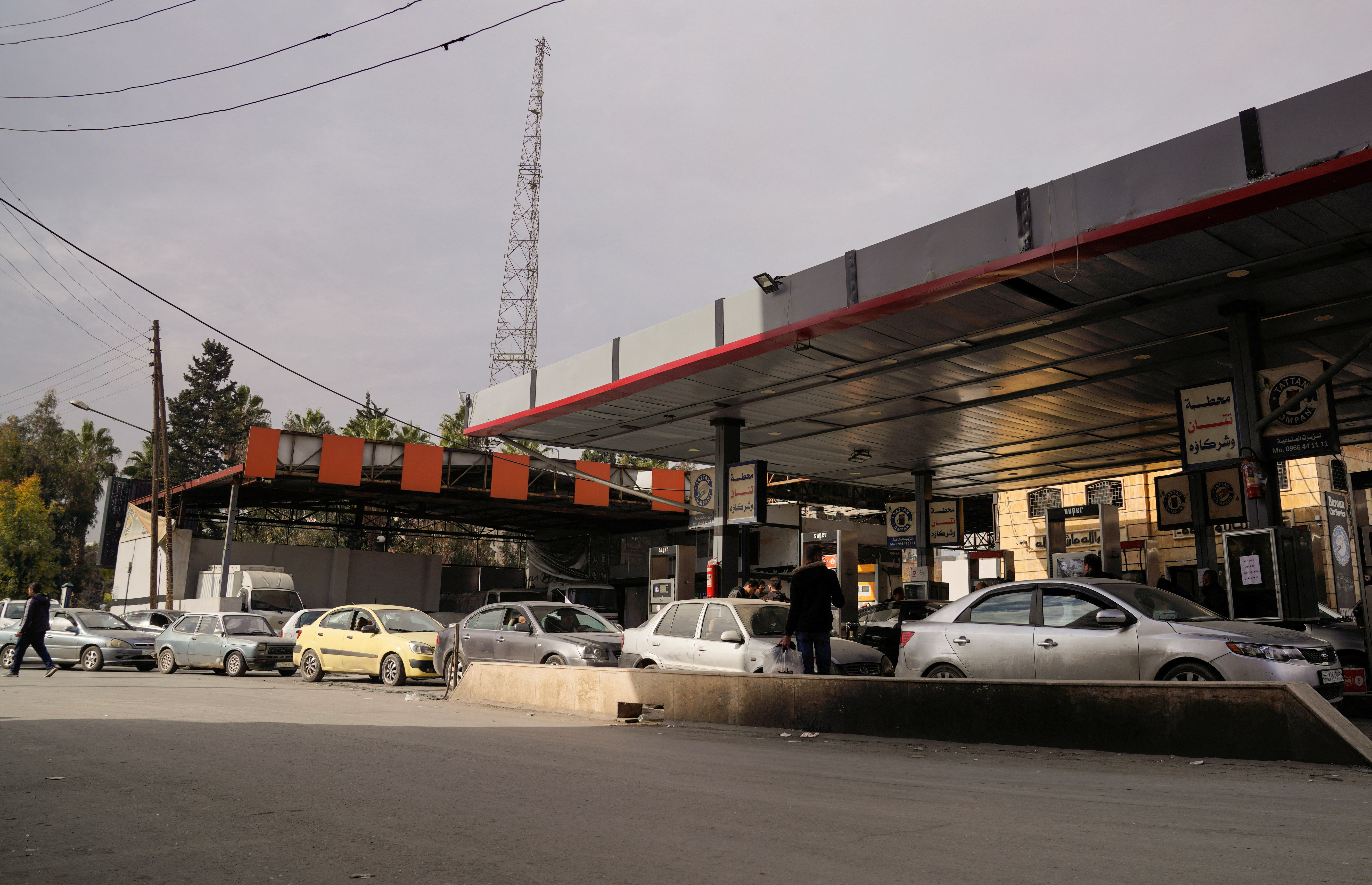 People queue as they wait to fuel up at a gas station in Aleppo