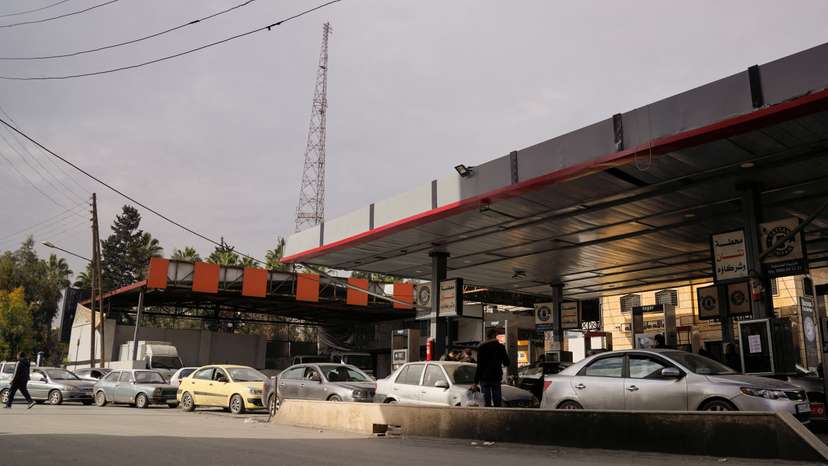 People queue as they wait to fuel up at a gas station in Aleppo