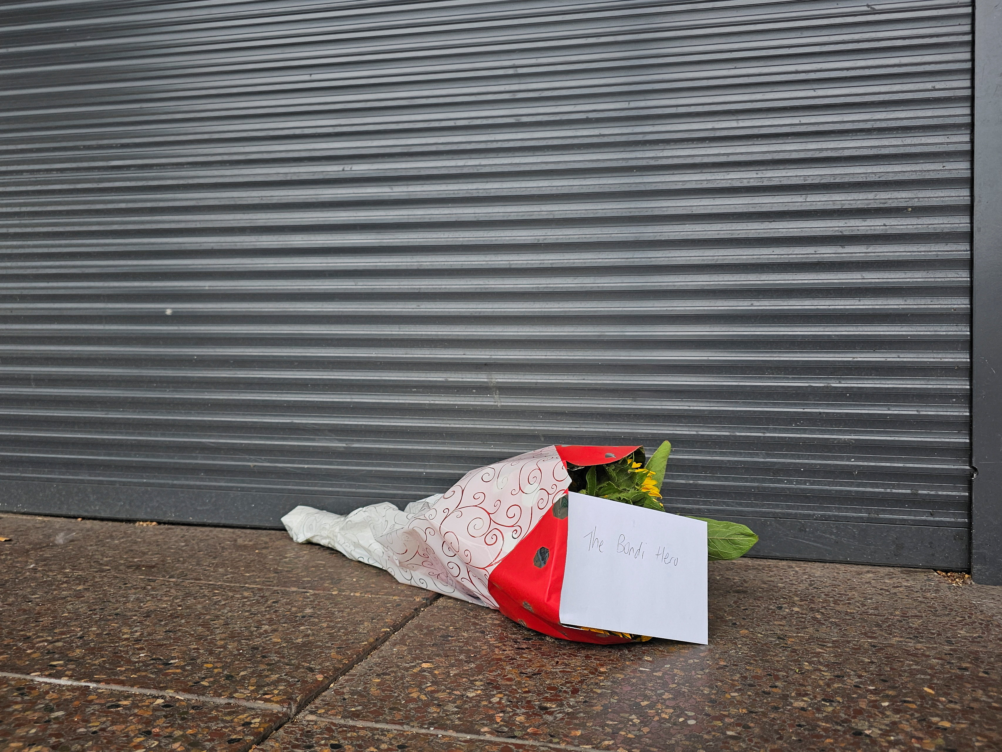 Flowers left outside tobacco shop owned by "Bondi hero" Ahmed al Ahmed, in Sydney